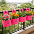 Pink hanging planters with flowers on a balcony railing 